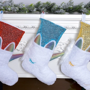 Three sequined unicorn Christmas stockings hanging on fireplace with pine branch decor