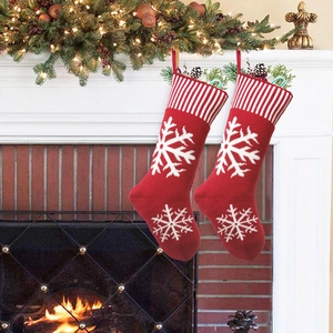 Close-up of red knitted Christmas stockings with snowflake patterns hung by a fireplace