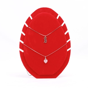 Detail of silver heart and fluid pendant necklaces on a red velvet jewelry stand