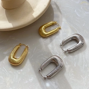 U-shaped ribbed gold and silver metal hoop earrings on marble textured surface