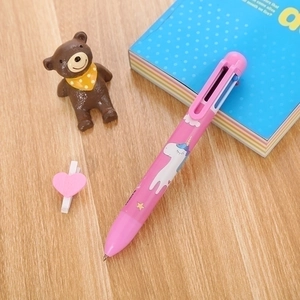 Cute pink 6-color unicorn ballpoint pen for students on a cozy wooden desk with notebook