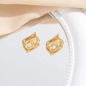 Polished golden interlocking hollow hoop earrings on elegant silk background