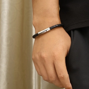 Close-up of men's black braided leather bracelet with silver clasp worn on a wrist