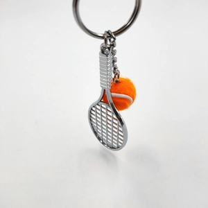 Metal tennis racket and orange ball keychain set with realistic texture on white background