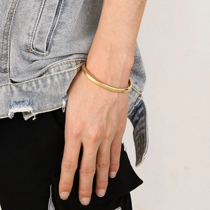 Primer plano de un brazalete en C de 6 mm de acero de titanio dorado usado en la muñeca