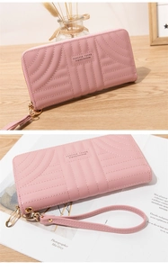 Pink quilted long wallet detail with golden zipper and wristlet on a wooden table
