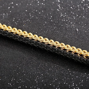 Macro detail of men's layered bracelet with gold braided metal and black leather strap
