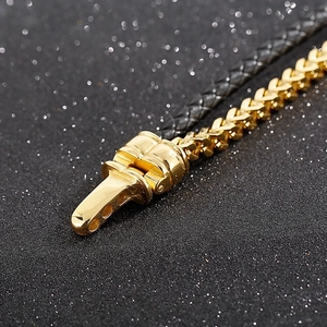 Close-up of golden spring buckle clasp and black woven leather chain on the bracelet