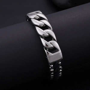 Detail of men's stainless steel Cuban chain linked with black braided leather cord