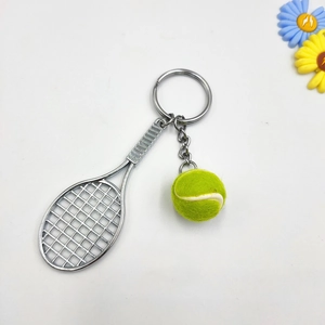 Detailed view of silver metal tennis racket keychain with a fuzzy yellow tennis ball charm