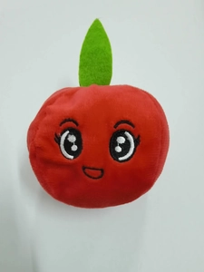 Detail of red apple plush dog toy featuring embroidered expression and green leaf decoration