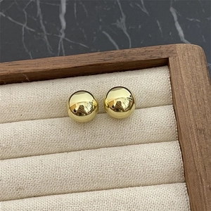 Macro detail of high-polish gold ball stud earrings displayed on a soft jewelry tray