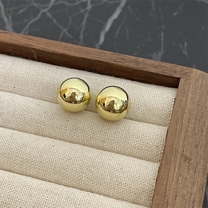 Minimalist high-polished gold ball stud earrings shown on a premium jewelry display tray