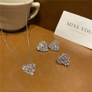 Three-piece heart jewelry set with sparkling pavé zircons on a dark leather surface