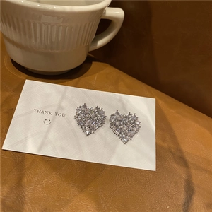 Detailed view of silver heart earrings with sparkling cubic zirconia on gift card