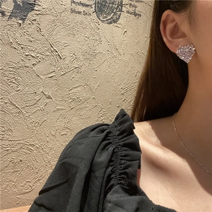 Elegant silver heart stud earrings with sparkling pavé zircons worn by a model