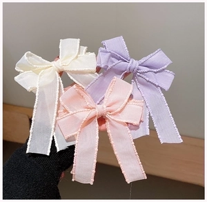 Detailed view of layered translucent bow hair clips with pearl-edge finish in pastel colors