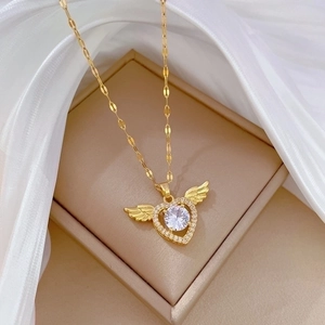 Gold winged heart necklace with sparkling crystal inlay displayed on white silk in box