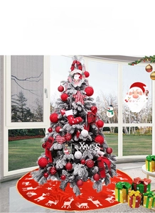 Detail of a flocked Christmas tree with red baubles, plaid bows and a reindeer tree skirt