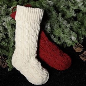Classic knitted Christmas stockings in cream and dark red on green pine branches
