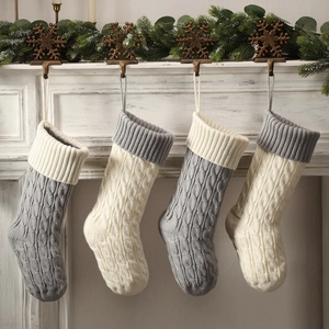 Set of 4 cable knit Christmas stockings in ivory and grey hanging on a white fireplace
