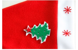 Detail of red Christmas hat showing green felt tree and snowflake applique texture