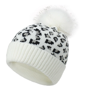 Women's leopard knit beanie hat with large white faux fur pompom in a 45-degree angle view