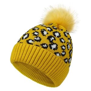 Detail of knit beanie with yellow leopard pattern and a large faux fur pompom ball