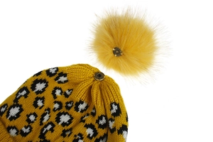 Detail of the snap button on yellow leopard knit hat with a faux fur pom pom