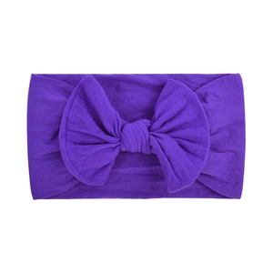 Detail of soft purple nylon baby headband featuring a large knitted bow on a white background