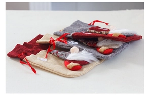 Close-up of three burlap Christmas gnome drawstring gift bags in red, grey and beige