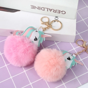 Close-up of pink and peach faux fur unicorn pompom keychains with gold metal rings