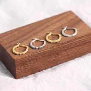 Detail of S925 sterling silver stud earrings with colorful gemstones on a wooden stand