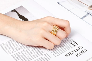 Close-up of a wide gold stainless steel ring with embedded zircon stones on a hand