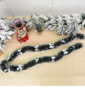 Detail of dark green Christmas tinsel with white snow tips and silver bows decor
