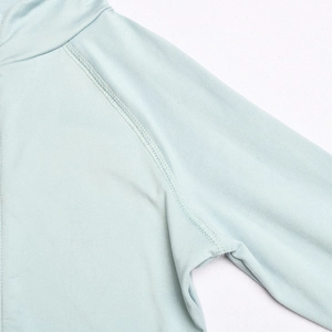 Detailed close-up of light green activewear showing raglan sleeve seams and stitching