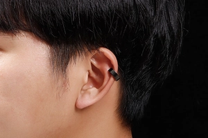 Gros plan d'un ear cuff noir en métal sur l'oreille d'un modèle pour oreilles non percées