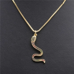Golden snake pendant necklace with multi-colored zircons on black leather background