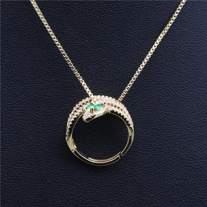 Detailed close-up of gold snake pendant with cubic zirconia and green eyes on black leather