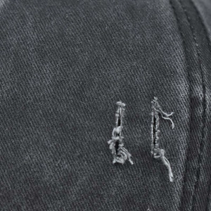 Detailed macro shot of dark grey washed cotton fabric with vintage distressed ripped effects
