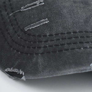 Macro detail of distressed washed denim fabric with ripped holes and reinforced stitching