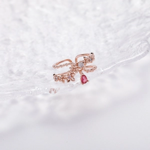 Detail of rose gold flower ring with micro-set diamonds and a pear-shaped red gemstone