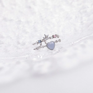 Macro shot of a silver heart-shaped blue crystal ring with floral accents and beads