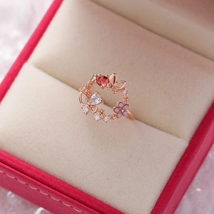 Close-up of rose gold flower ring with red crystals and butterfly detail in a gift box