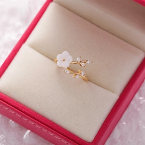 Macro shot of gold flower ring with white petals and zircons in a pink jewelry box
