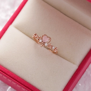 Detailed close-up of rose gold flower ring with pink heart stone in a velvet jewelry box