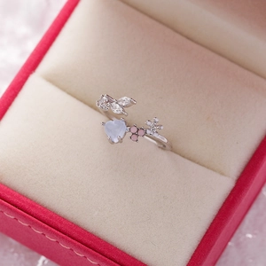Macro shot of open ring with blue heart crystal, enamel flowers and cubic zirconia leaf