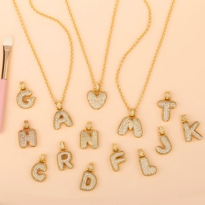 Macro detail of gold-tone initial pendants with pave-set cubic zirconia on necklaces