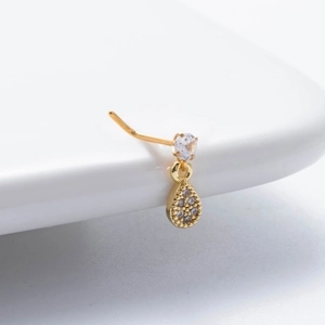 Gold nose stud with round clear gem and dangling teardrop zircon pendant on white surface
