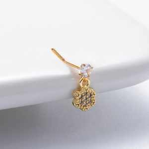 Detailed view of a gold nose stud featuring a crystal flower pendant on a ceramic tray